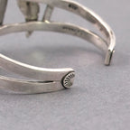 Close-up of silver-tone cuff bracelet end with small sunburst detail