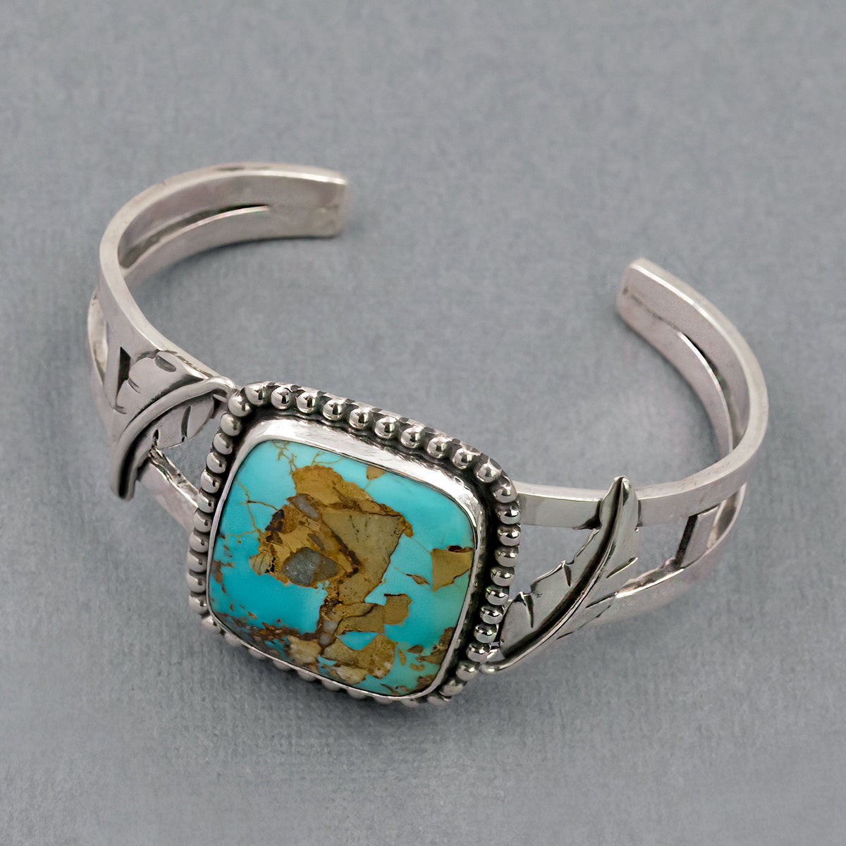 Silver bracelet with turquoise oval stone center and leaf-like side cutouts