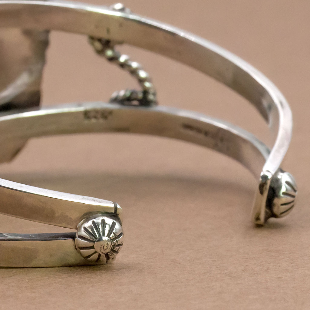 Sterling silver cuff bracelet close-up of engraved inner band and floral end accents.