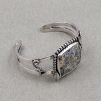 Sterling silver cuff bracelet with jasper cabochon, beaded edge and dangling chain links.