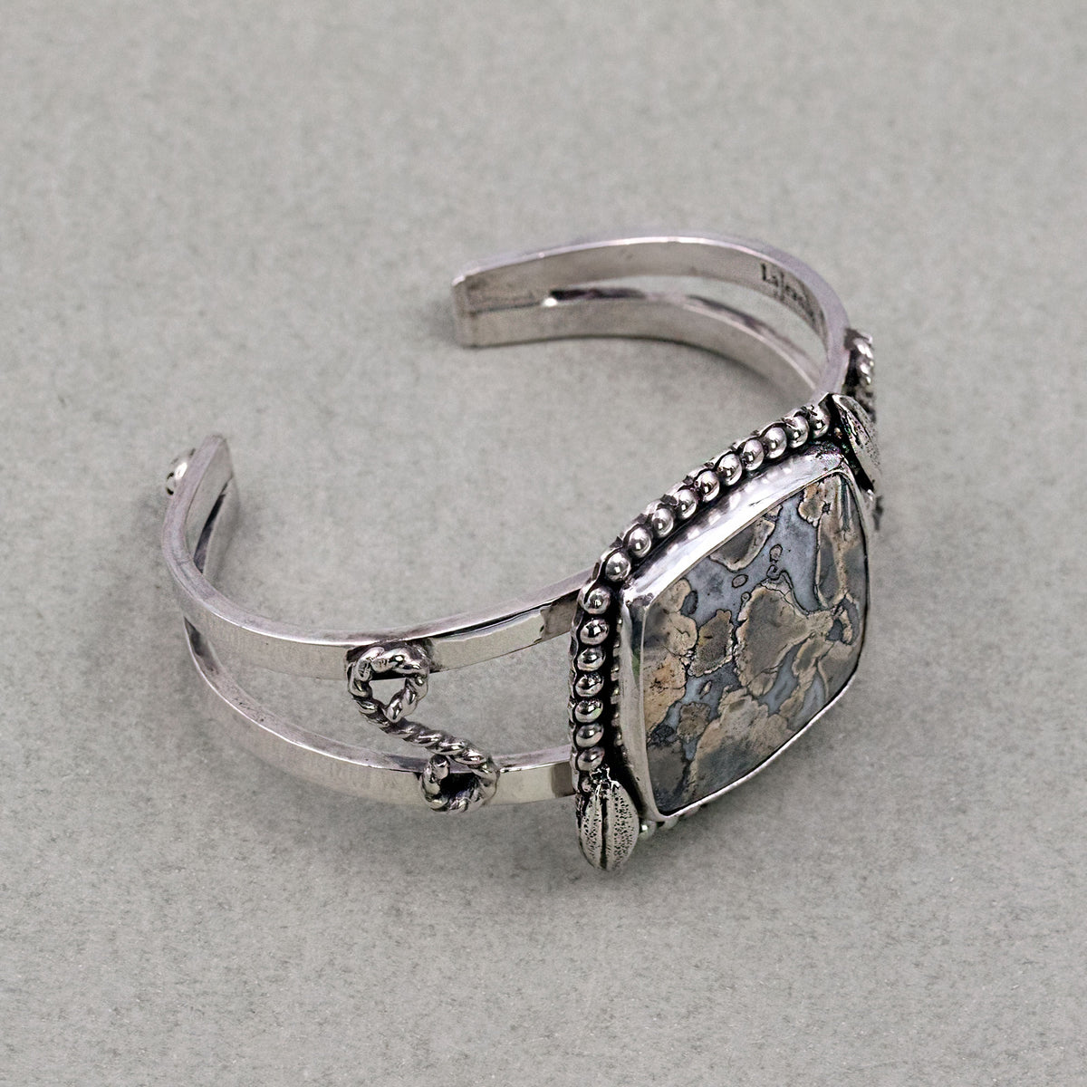 Sterling silver cuff bracelet with jasper cabochon, beaded edge and dangling chain links.