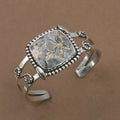 Sterling silver cuff bracelet with framed jasper cabochon and braided chain accents.