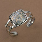 Sterling silver cuff bracelet with framed jasper cabochon and braided chain accents.