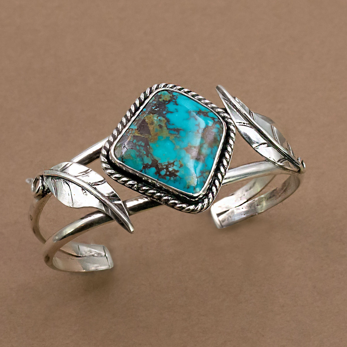 Sterling silver cuff bracelet with turquoise cushion center stone and openwork leaves