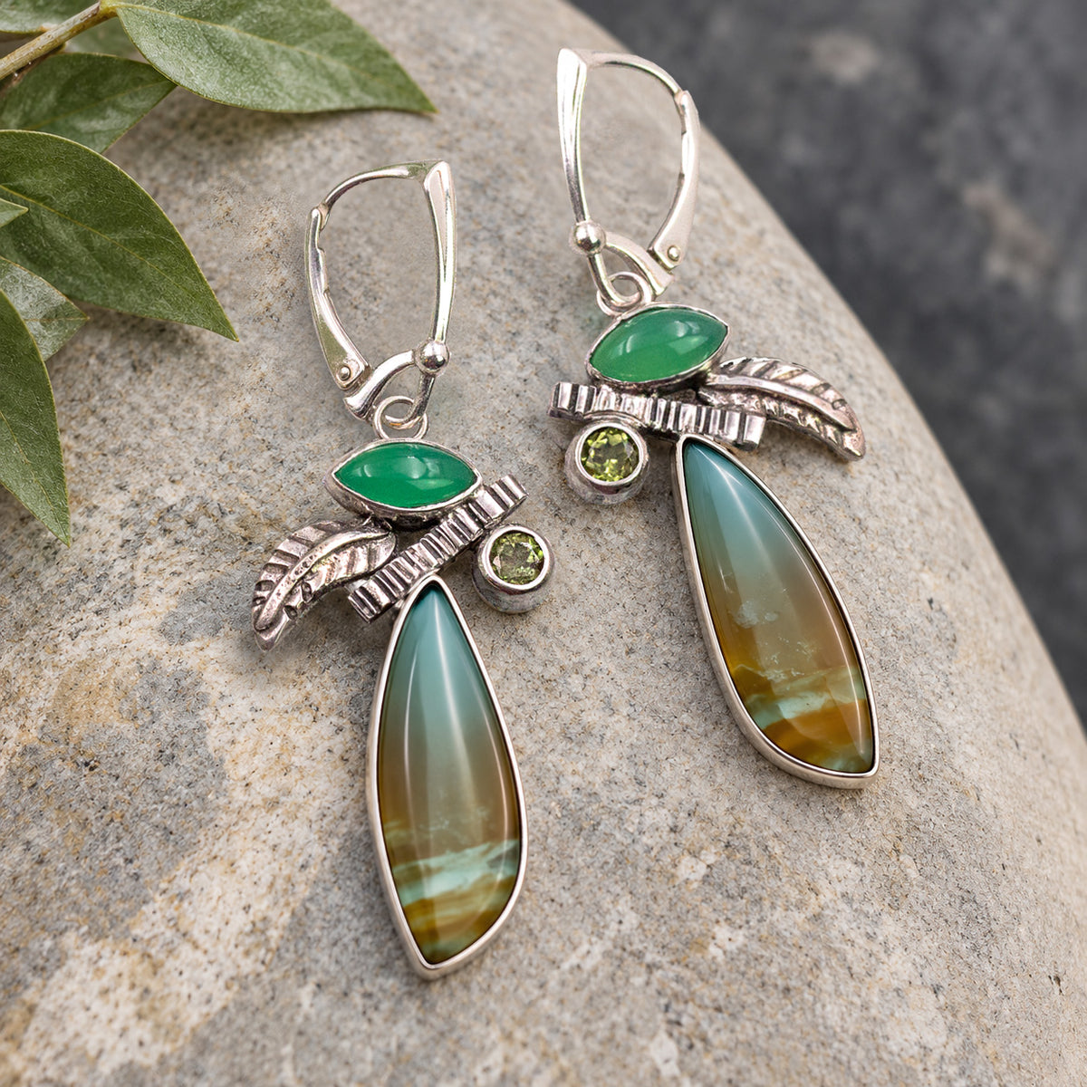Sterling silver drop earrings with green stones, textured accents, and long, banded teardrop gems
