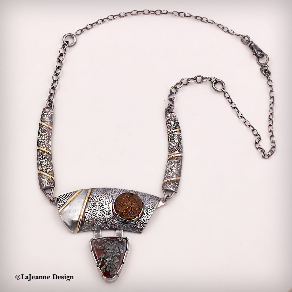 Silver statement necklace with textured stations, gold accents, round brown cabochon and drop