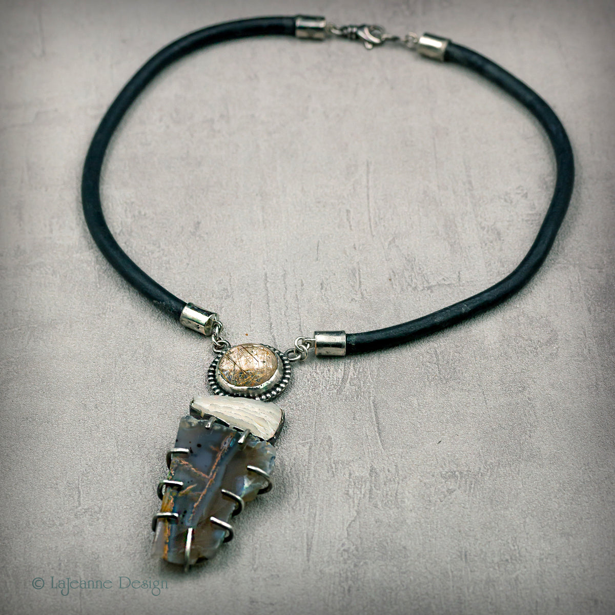 Gemstone pendant necklace with round cabochon and dark quartz cluster on black cord