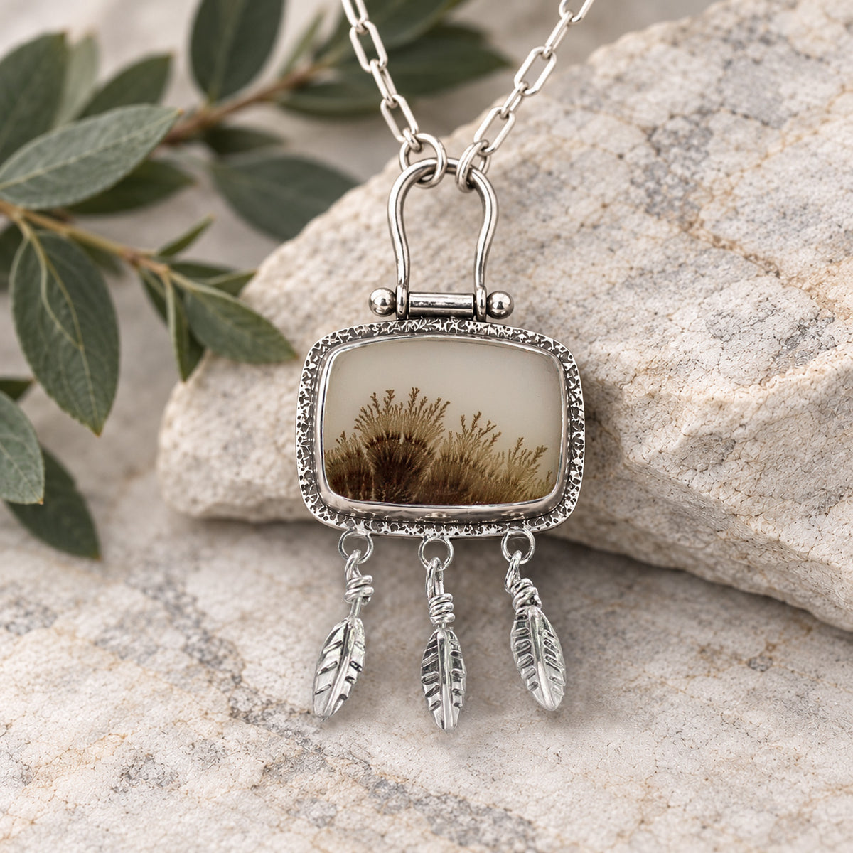 Silver necklace with rectangular gemstone pendant and three feather charms