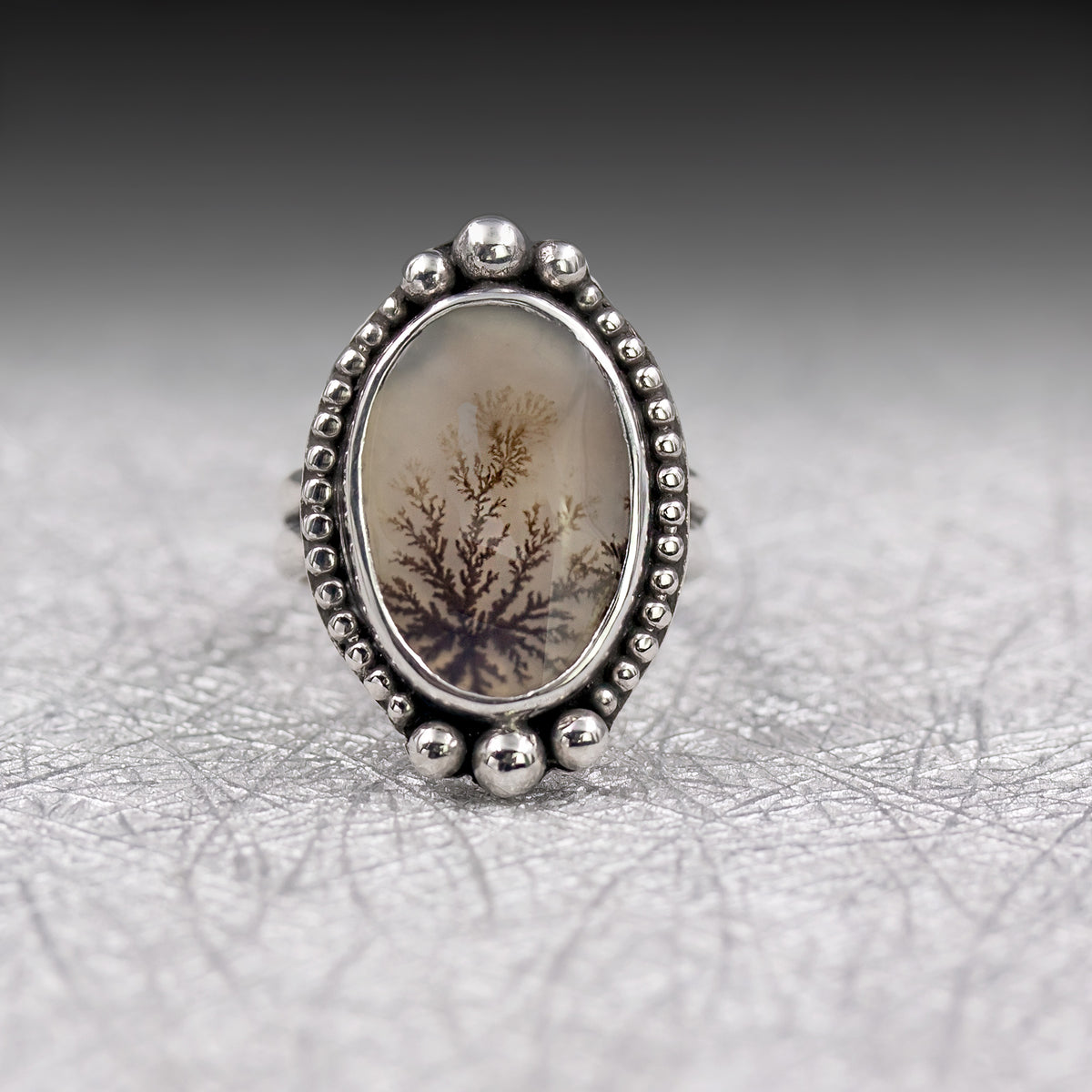 Size 7 sterling silver ring showing oval stone with framed dendrite pattern and beaded border